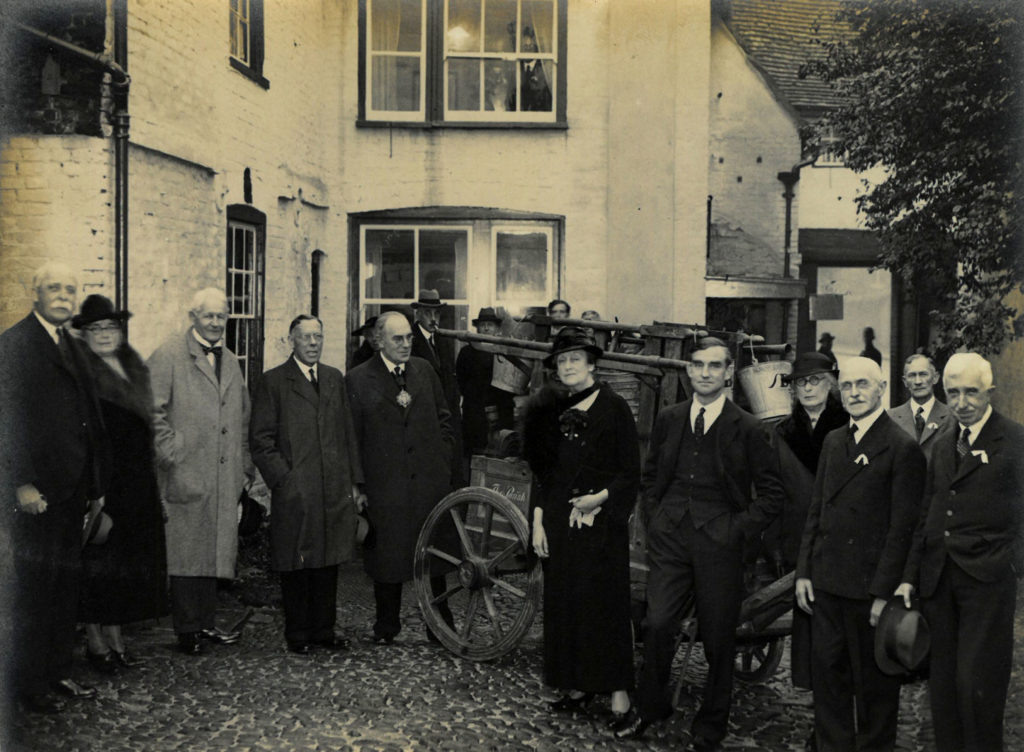 Image of the founders of the Museum of Cambridge. A black and white photograph of men and women gathered in the courtyard.